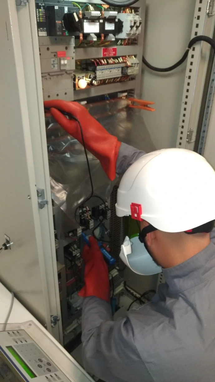 intervention d'un électricien portant des équipements de protection individuelle isolants, sur un panneau électrique 